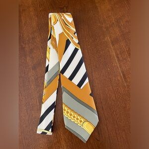 Hermes Men’s tie 100% silk in gold, white, gray and black pattern.
